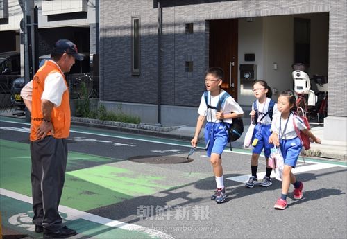 東京第1初中の児童・生徒たちの登校を見守る三河島分会の同胞（左）